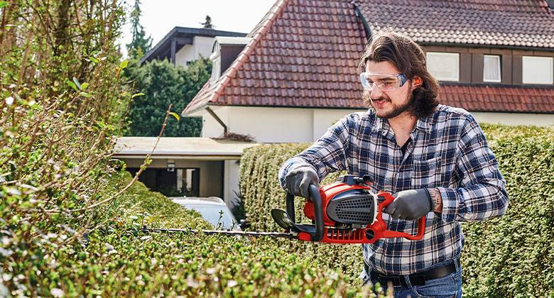 a man cuts the hedge with a hedge trimmer