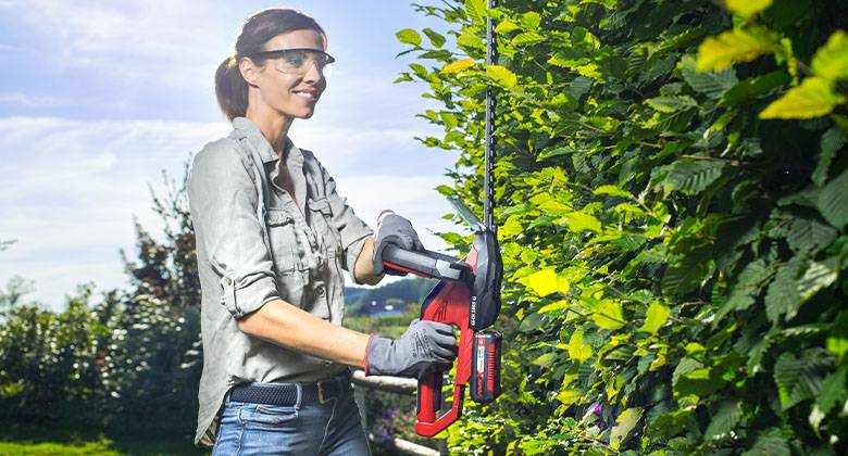 a woman cuts the hedge with hedge shears