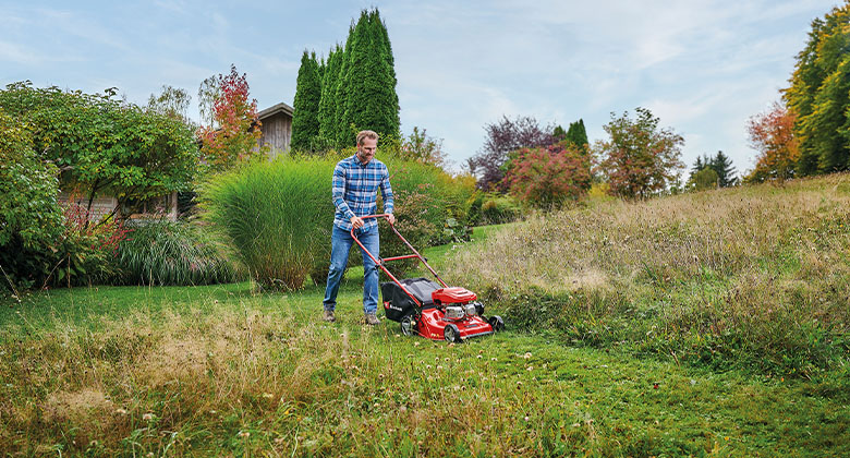 A man mowing a meadow with a powerful petrol lawnmower.