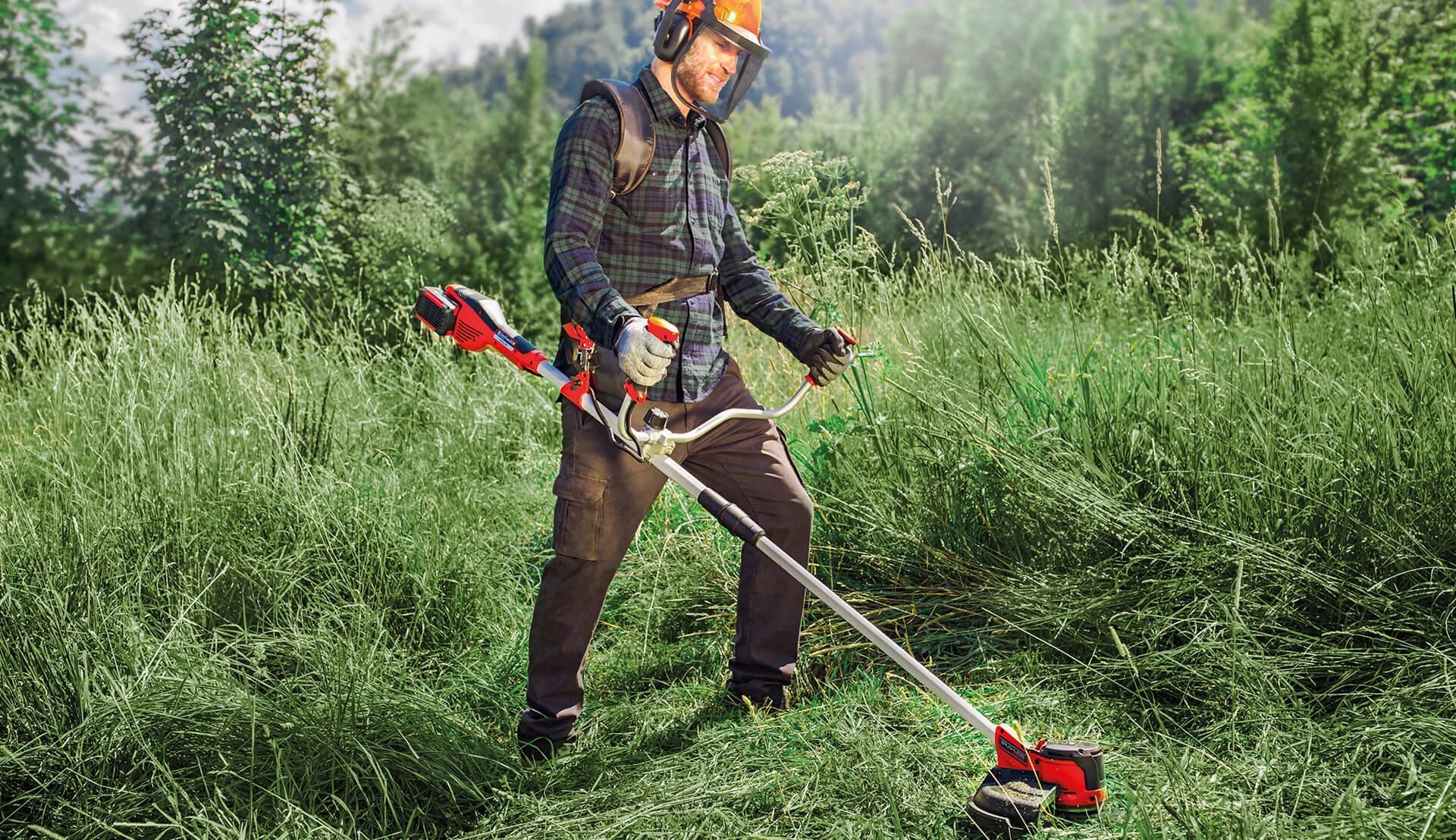 a man cuts the grass of a meadow with an electric scythe